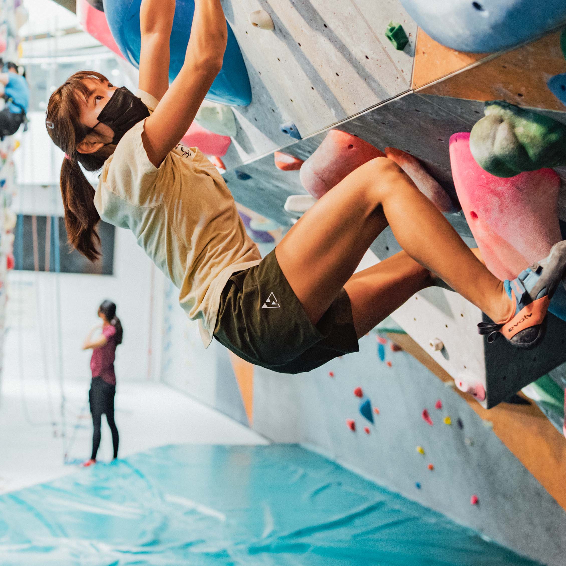 Climbing looking up mid-climb while bouldering indoors