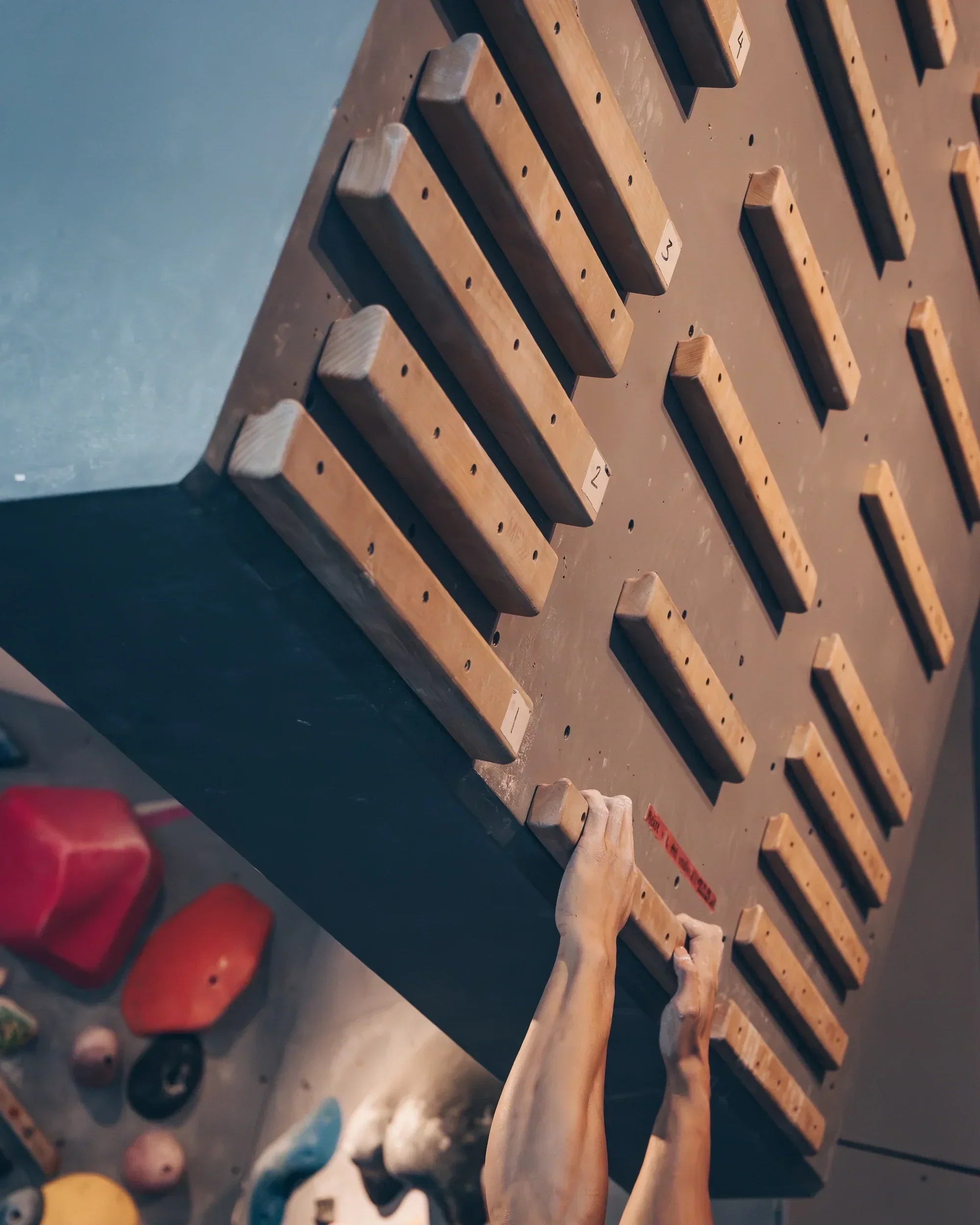 Close-up of climber's hands hanging on to campus rung
