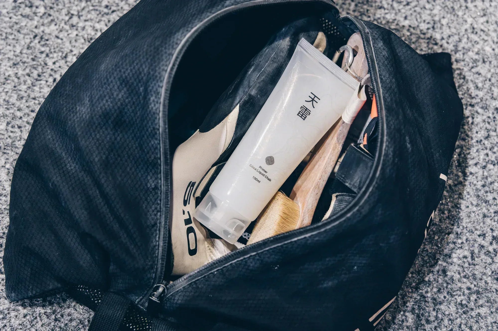 Open climbing gym bag containing Thunder liquid chalk, climbing shoes and a hold brush
