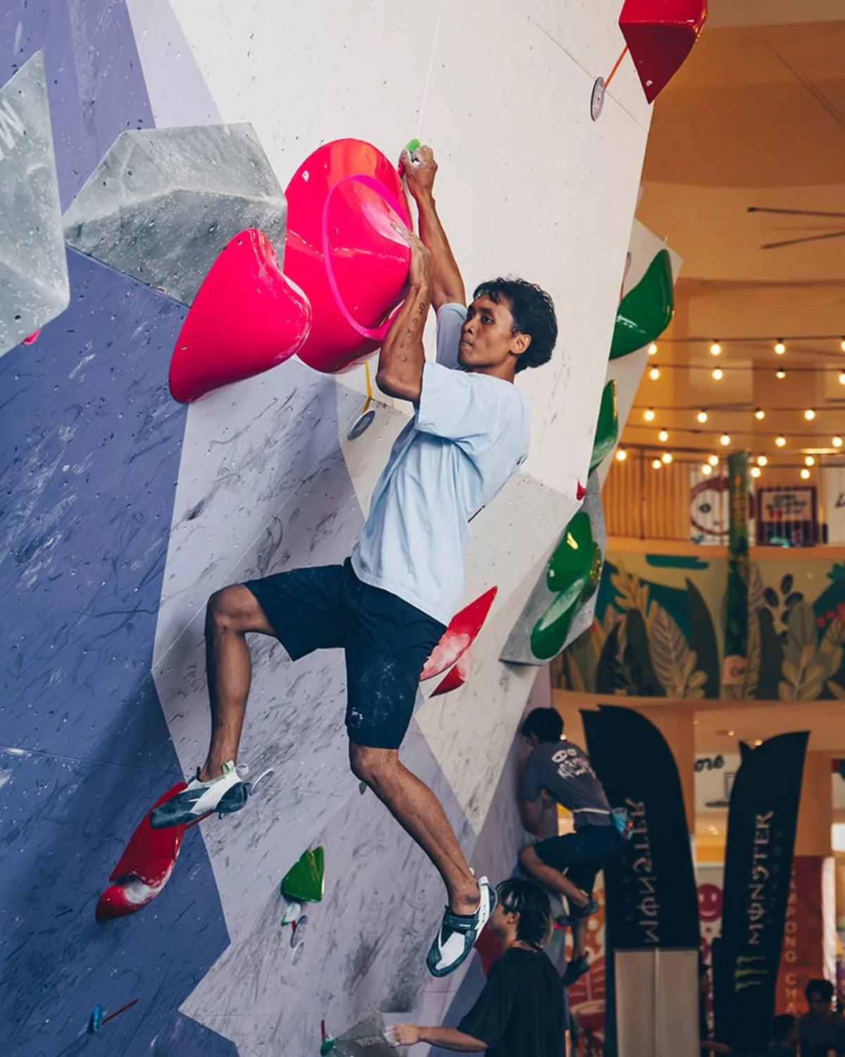 Male Climber Doing Dynamic Move on PInk Holds on Competition Bouldering Wall