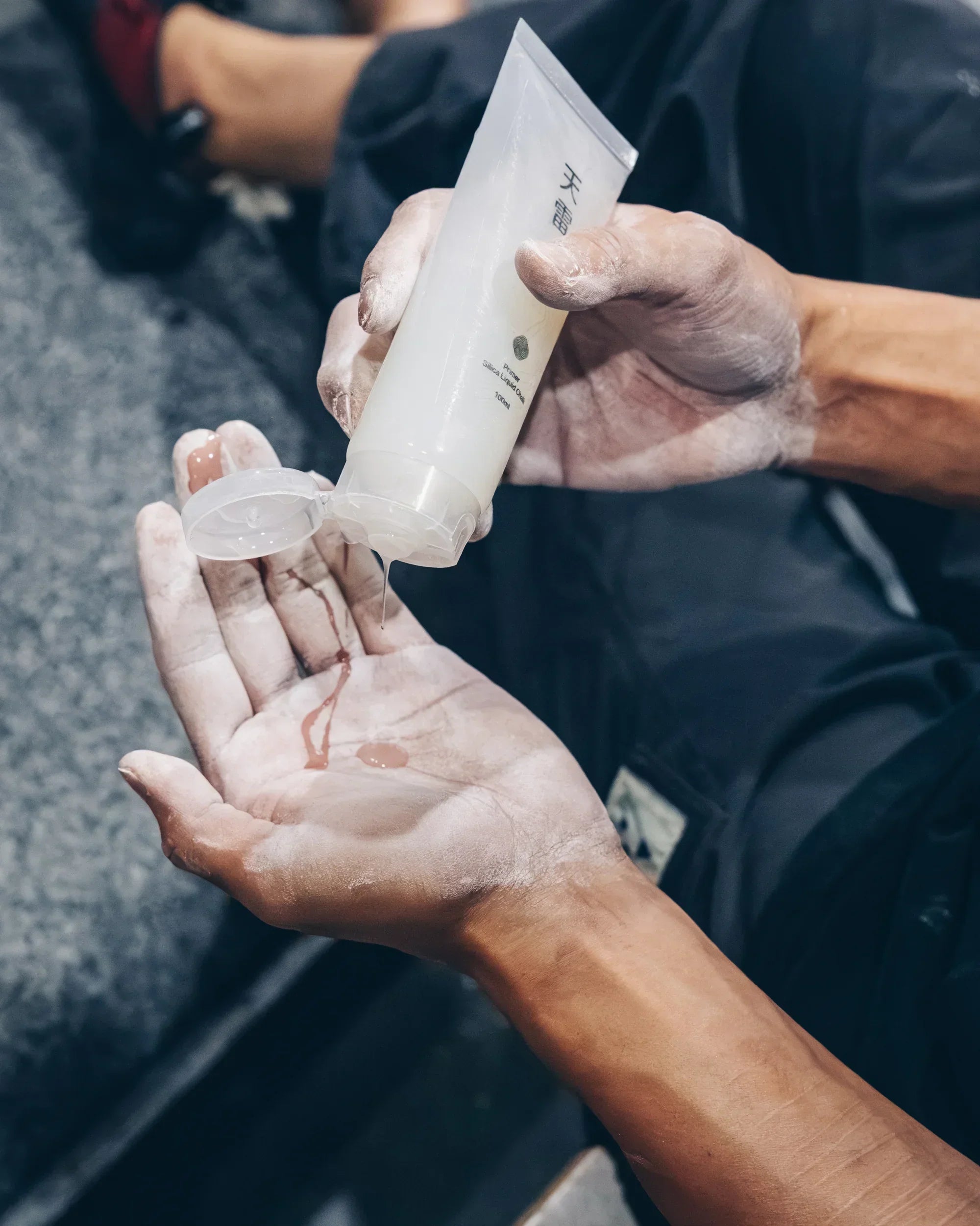 Climber applying Thunder silica liquid chalk to chalked hands before a climb