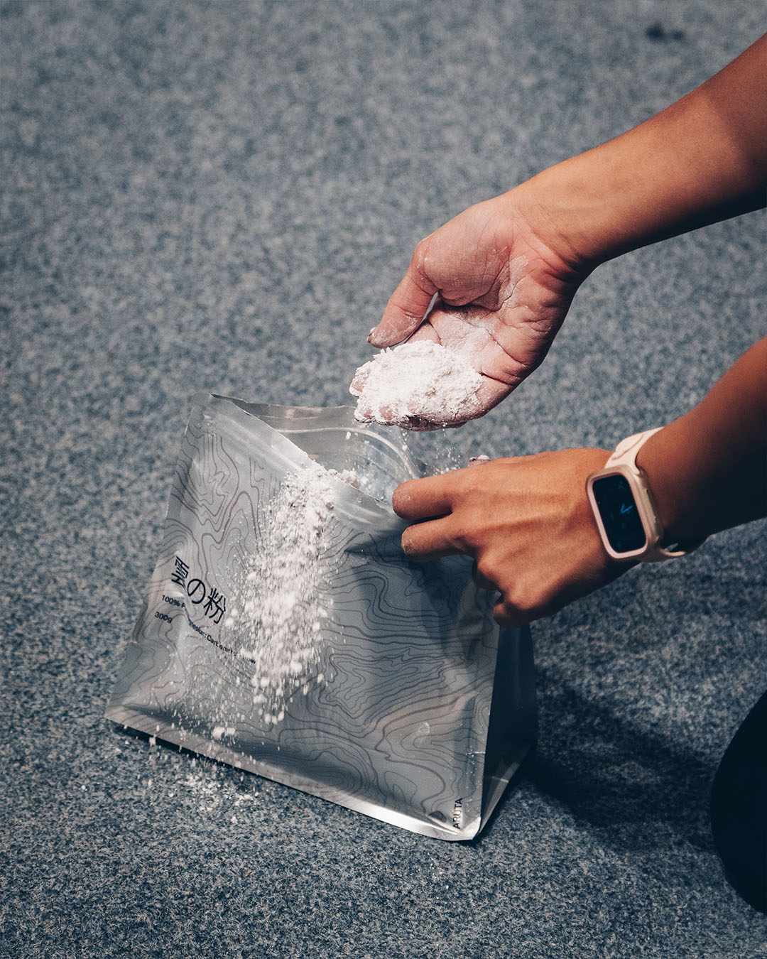 Climber scooping up a handful of KUMO chalk from packaging