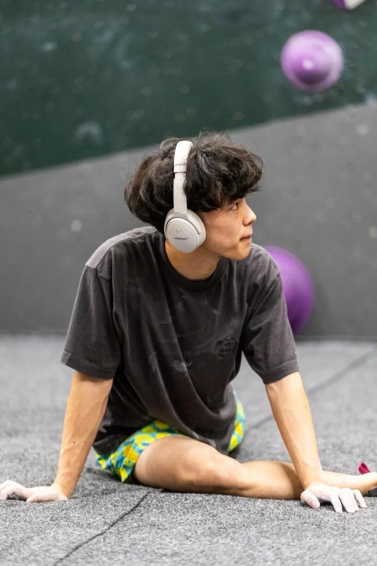 Male climber doing stretches to warm up on bouldering mat