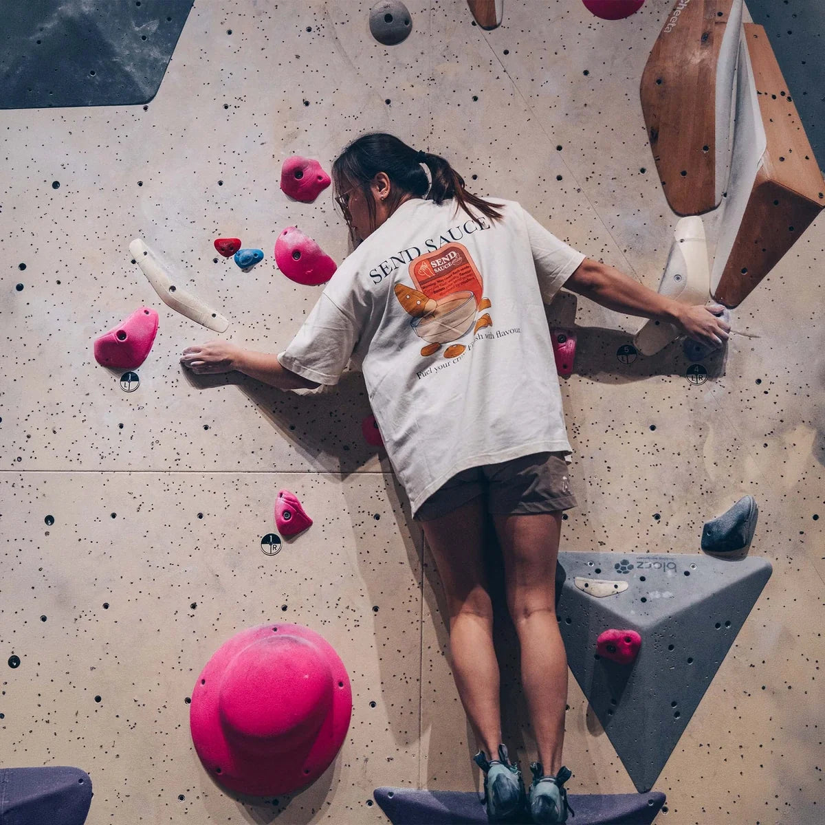 Female climber balancing on a volume on a colourful bouldering wall