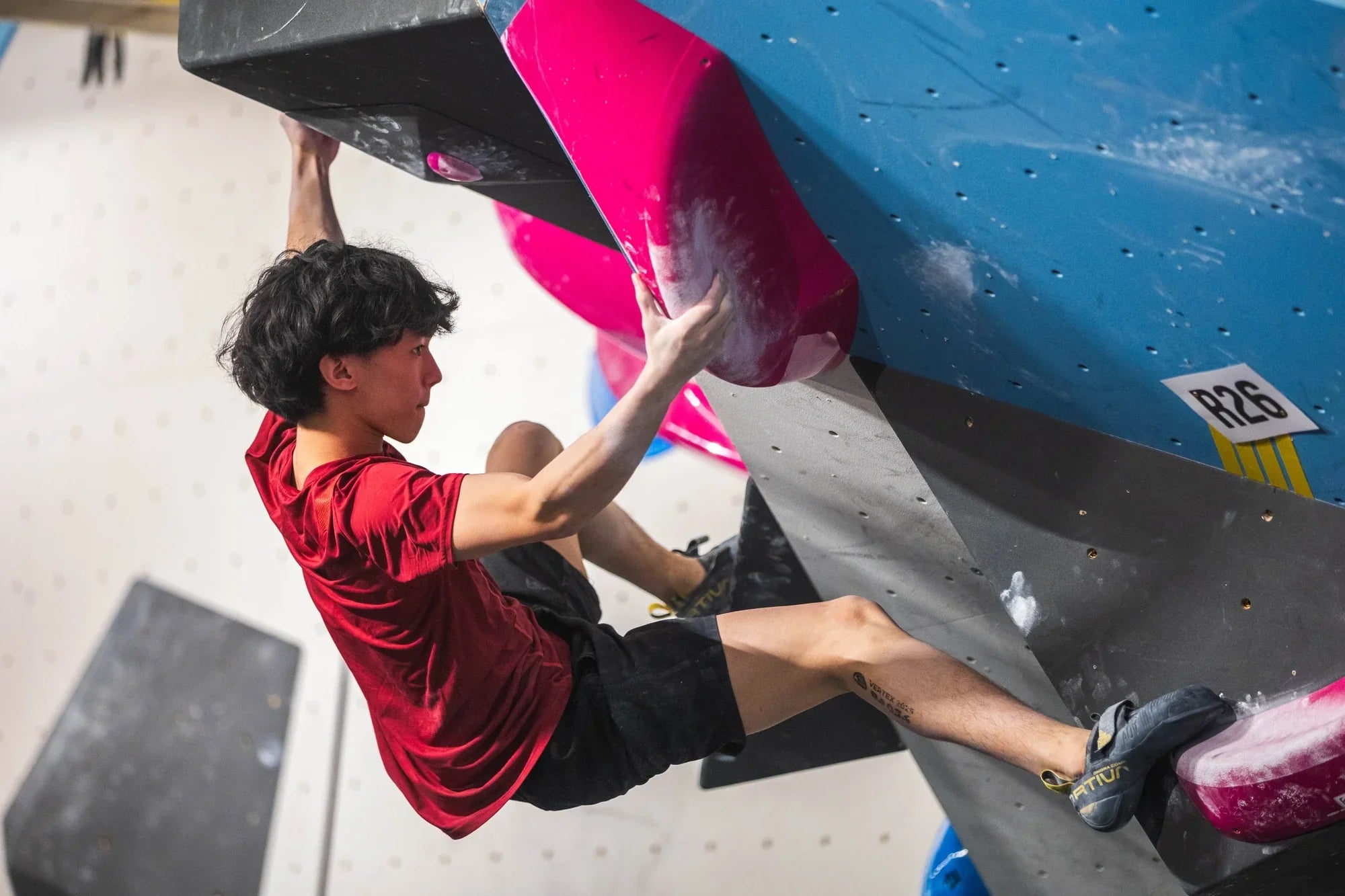 Male climber pulling hard on overhanging bouldering wall with muscles visible