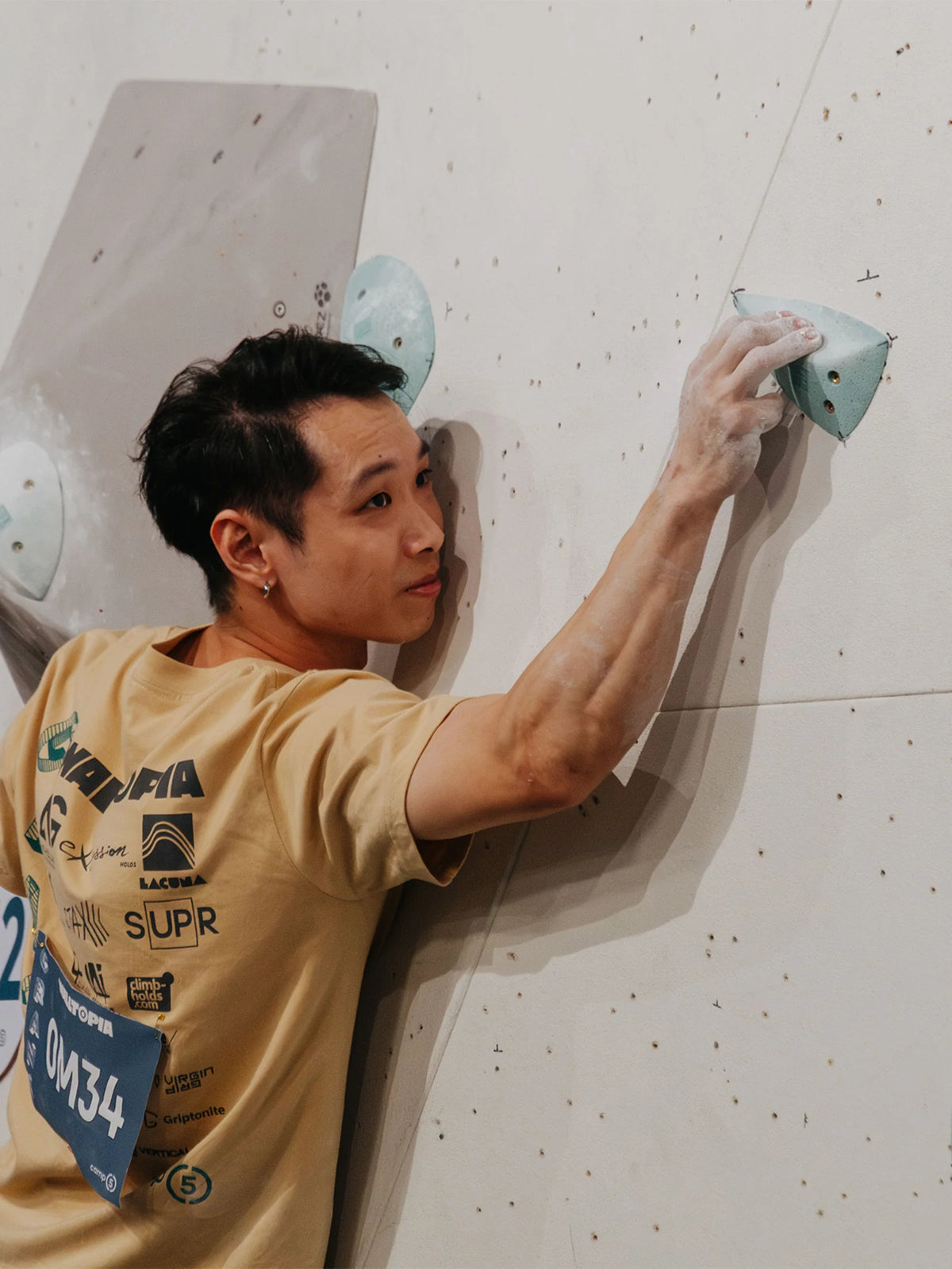 Male climber holding onto slopey crimp and balancing on slab boulder